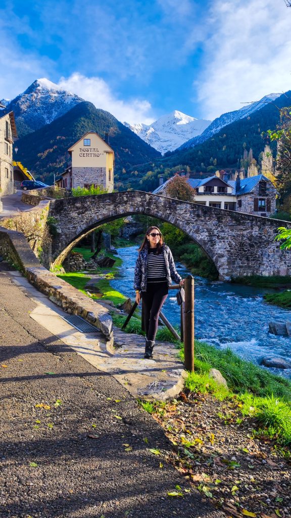 Puente histórico en Sallent de Gállego con las impresionantes montañas de los Pirineos como fondo, rodeado de naturaleza.