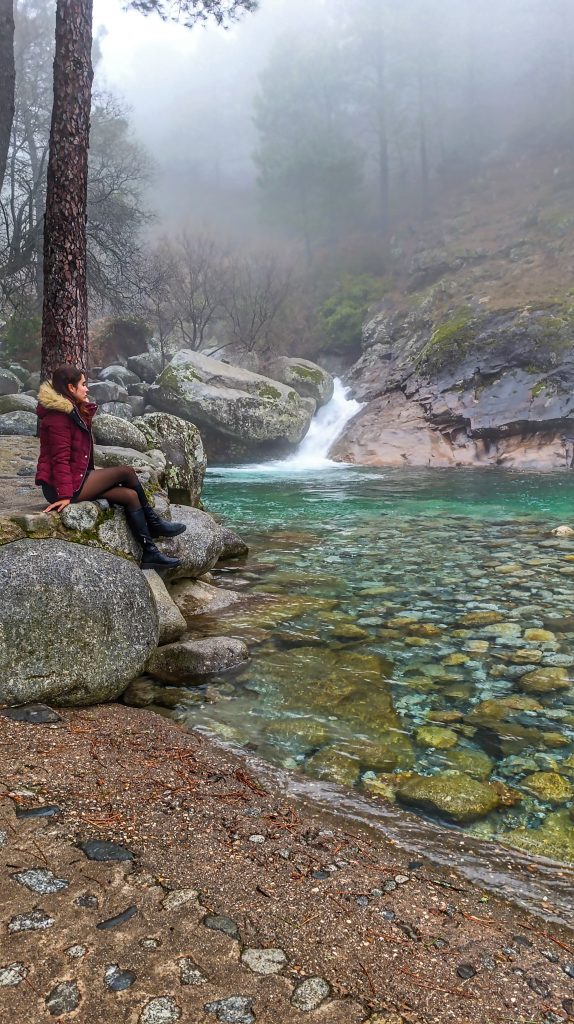 Paisaje del Charco Verde en la Sierra de Gredos, rodeado de rocas y vegetación, con una ligera niebla que crea un ambiente mágico y misterioso.