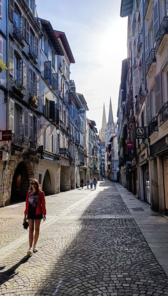 Chica en una de las calles más famosas de Bayona con las torres de la catedral al fondo