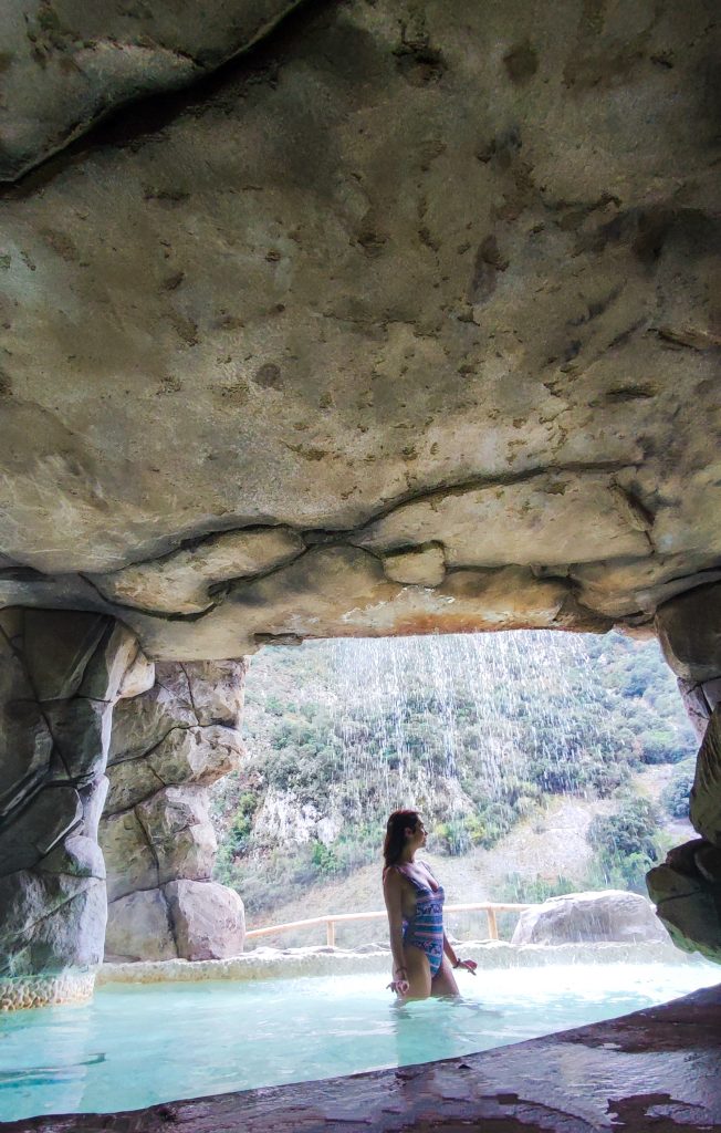 Chica en una piscina natural del Balneario de la Hermida con su cascada al fondo