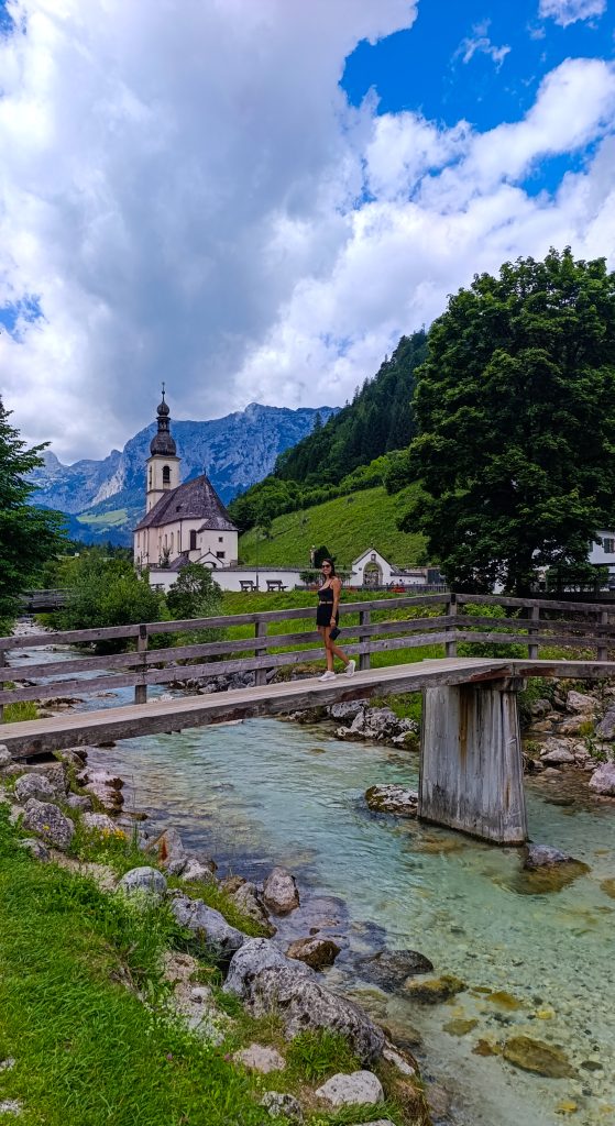 Chica en el puente con la famosa Iglesia de San Sebastián al fondo en los Alpes Bávaros
