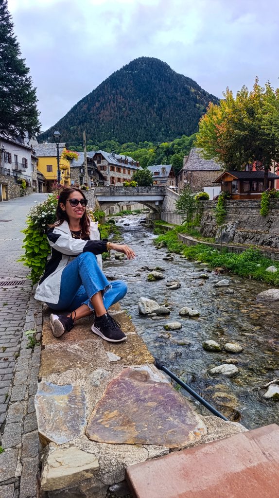 Chica sentada a la orilla del río en el pueblo de Tredós